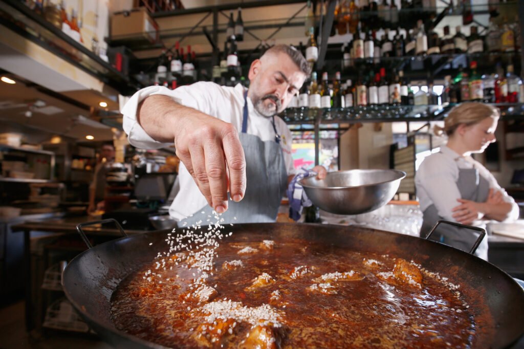 A Spanish Chef putting all his attention and love into the craft of cooking a Paella