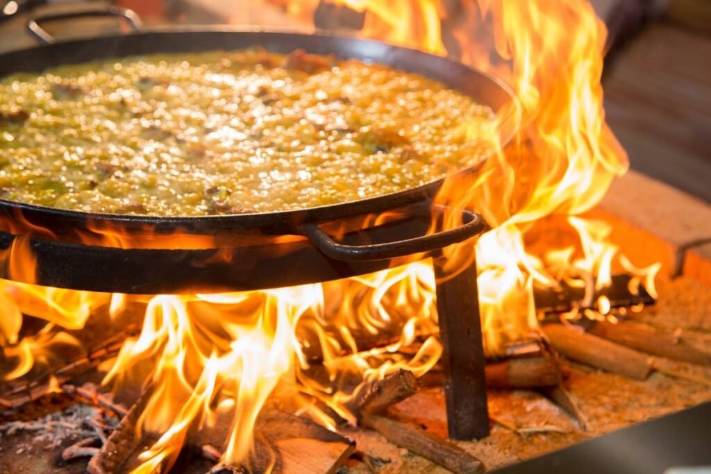 A beautiful picture of a Paella being cooked the traditional way, through burning wood